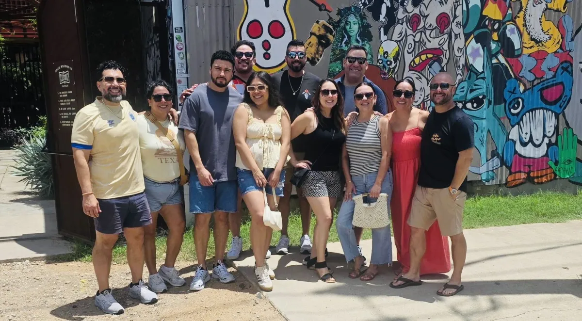 Bachelor and bachelorette group posing in front of an Austin street mural before their party bus night