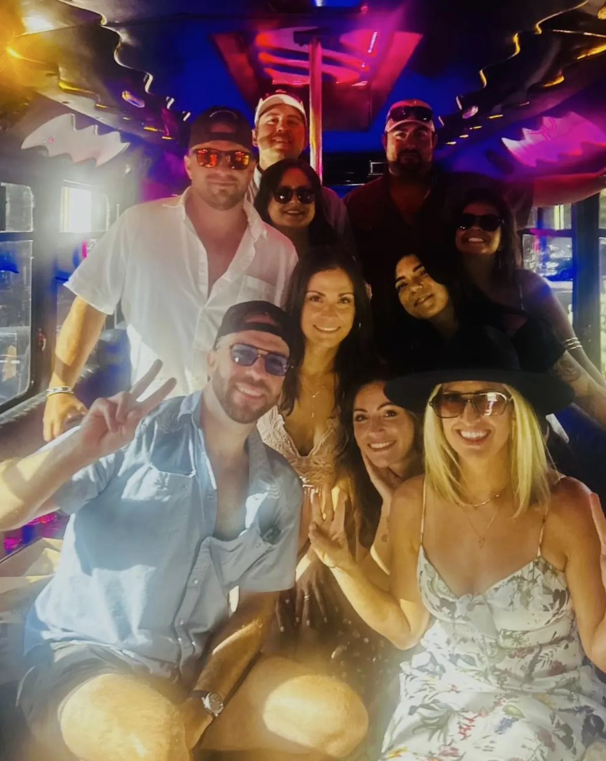 Mixed bachelor and bachelorette group taking selfie on Austin Party Bus with purple party lights